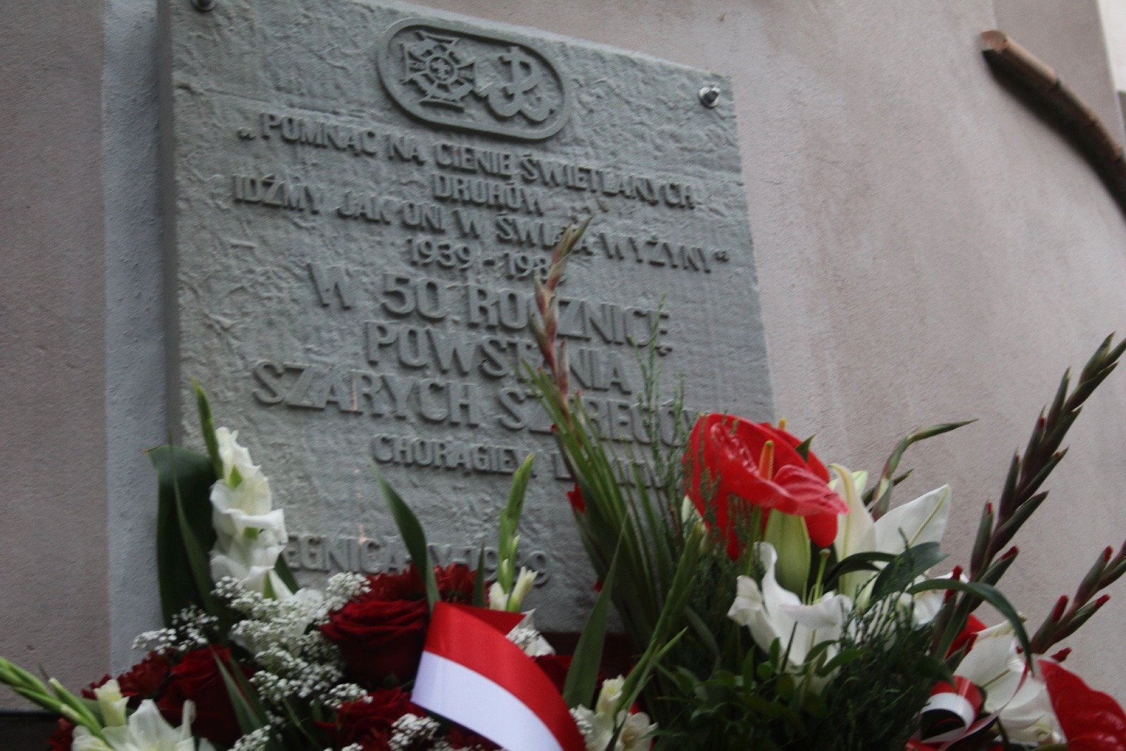 Kwiaty, znicze pod tablicą Szarych Szeregów w rocznicę powstania